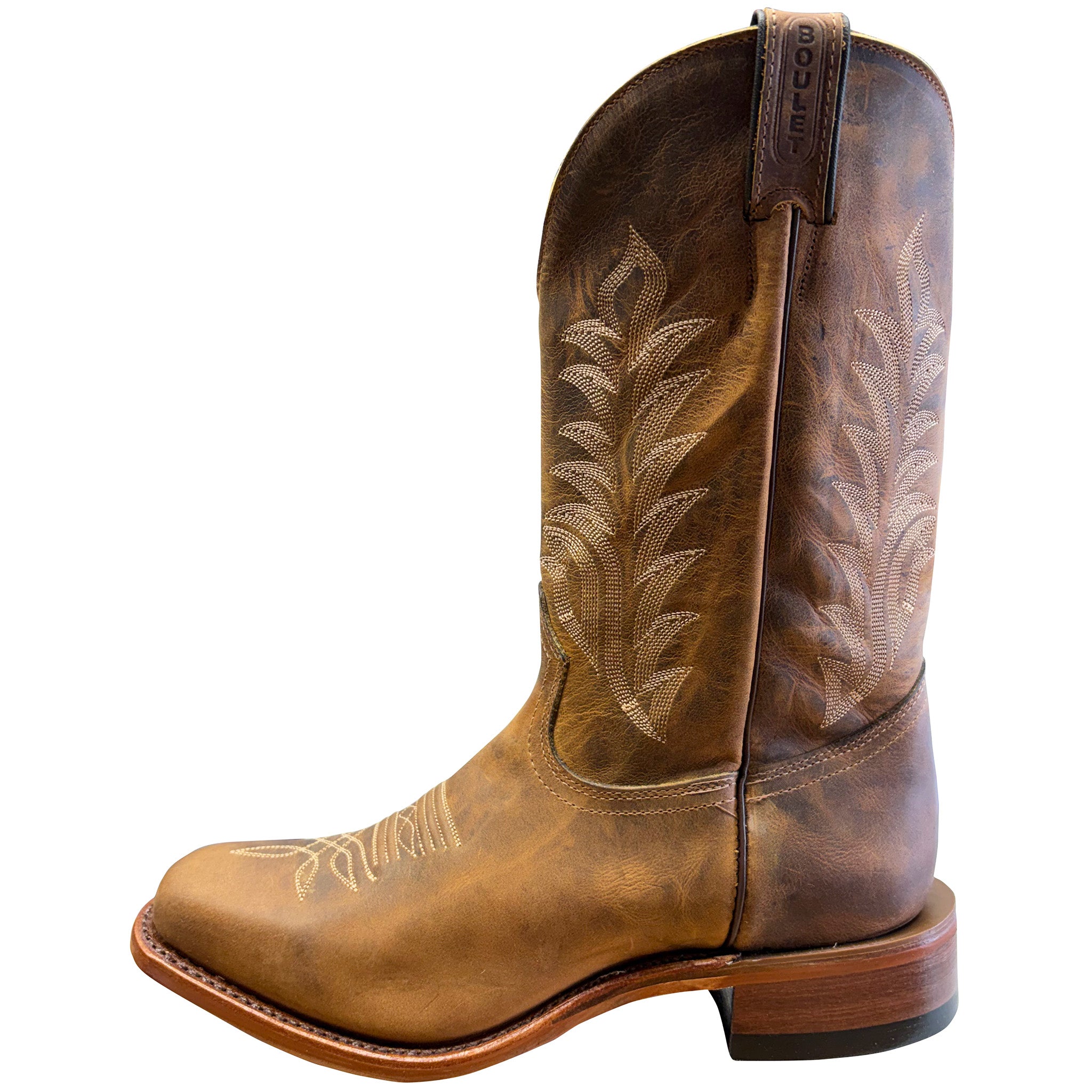 Brown cowboy boot with intricate embossing on a white background